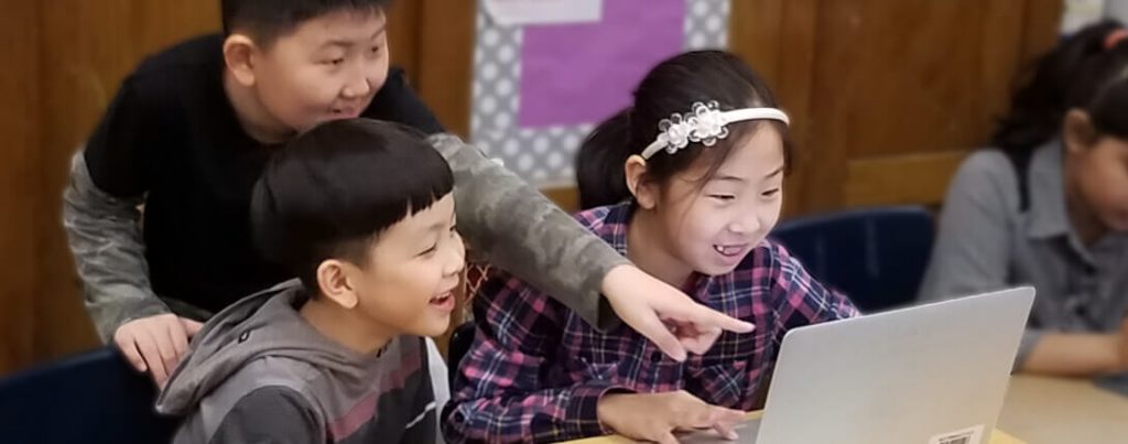 Three young Students pointing at laptop