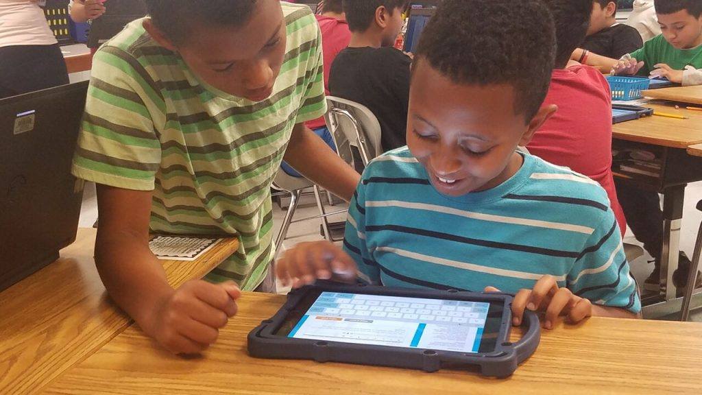 Two elementary students learning on a tablet