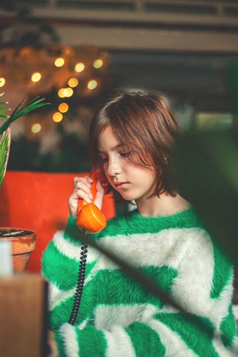 Tween girl using a corded phone at home, reflecting analog childhood through simpler, low-tech family life