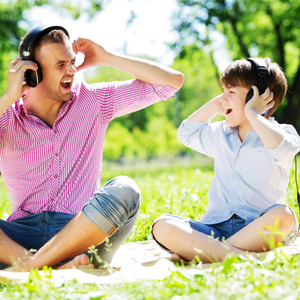 Father and son listen to music together on headphones, sharing a quiet moment of connection and discovery.